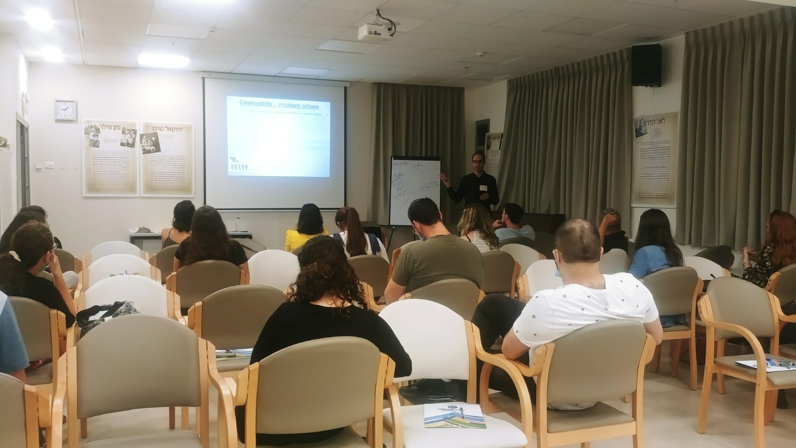 תמונה של צעירים יושבים באולם כנסים עם הגב למצלמה. 