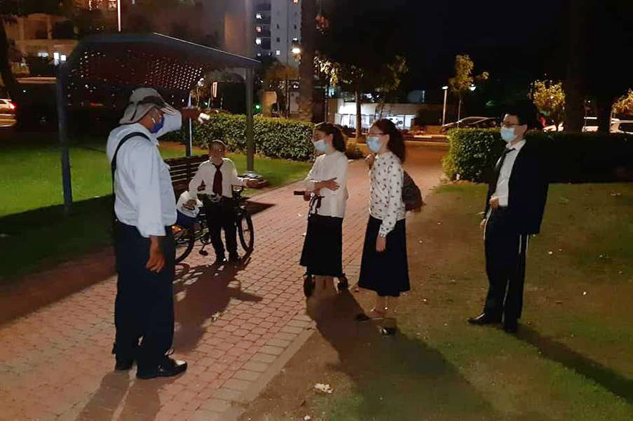 פקח משוחח עם תושבים צעירים בגינה ציבורית