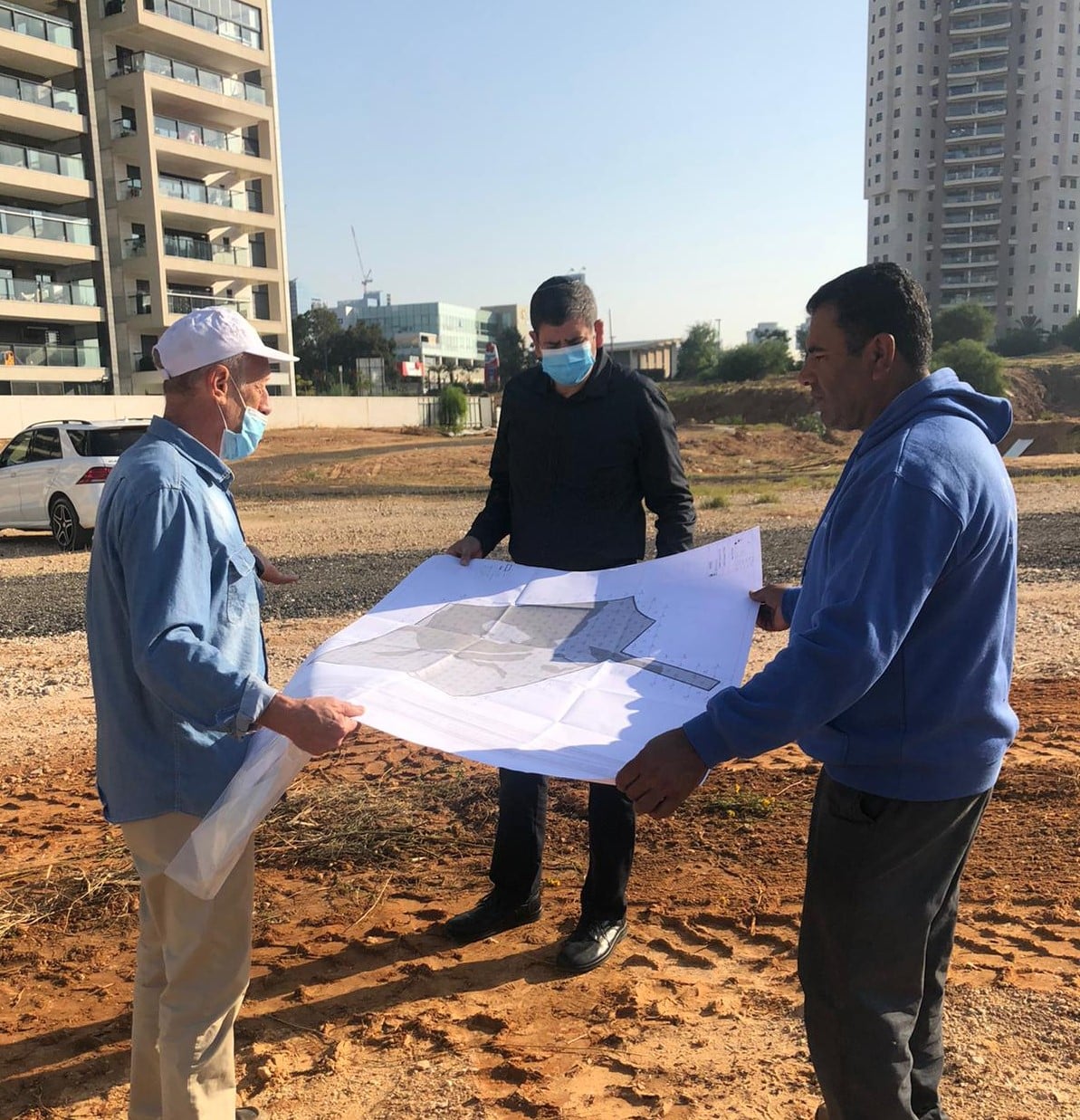 ראש העיר יוסי ברודני עם עובדי הבינוי של הפארק החדש עומדים באתר הבנייה אוחזים תוכנית הנדסית