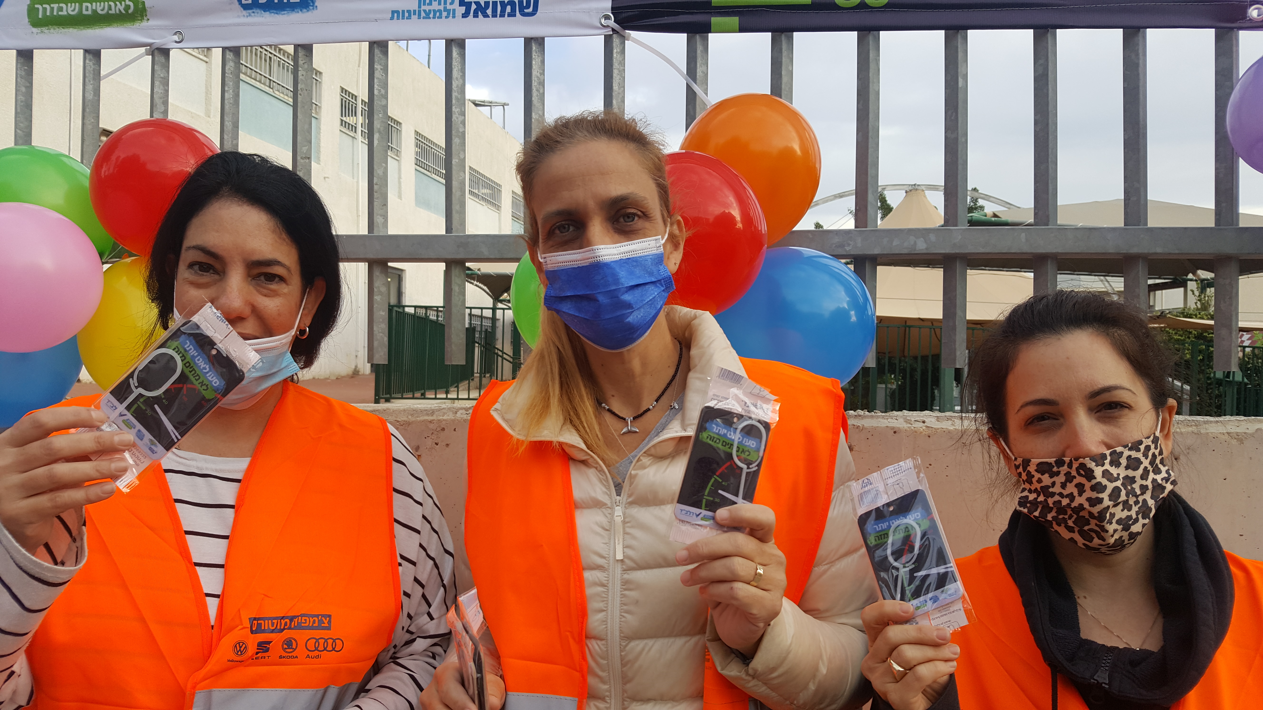 הורים לובשי וסט זהירות ועוטים מסכות מצולמים על רקע חצר בית ספר