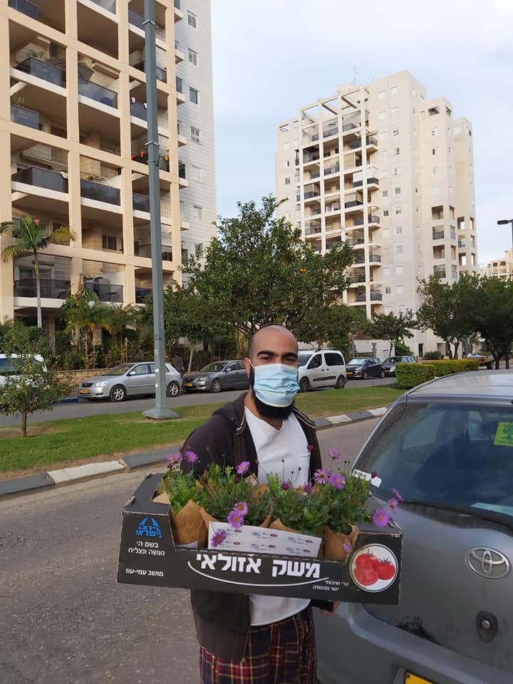 אדם אוחז בארגז עם שתילים