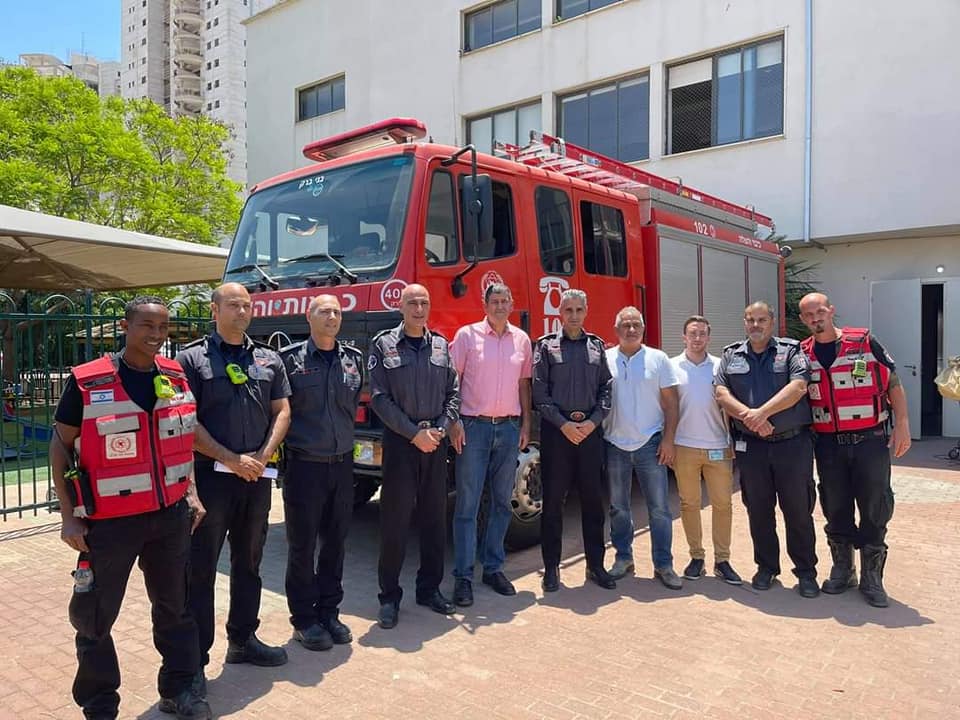 ראש העיר יוסי ברודני עם כבאים מצולמים כשברקע מכונית כיבוי אש